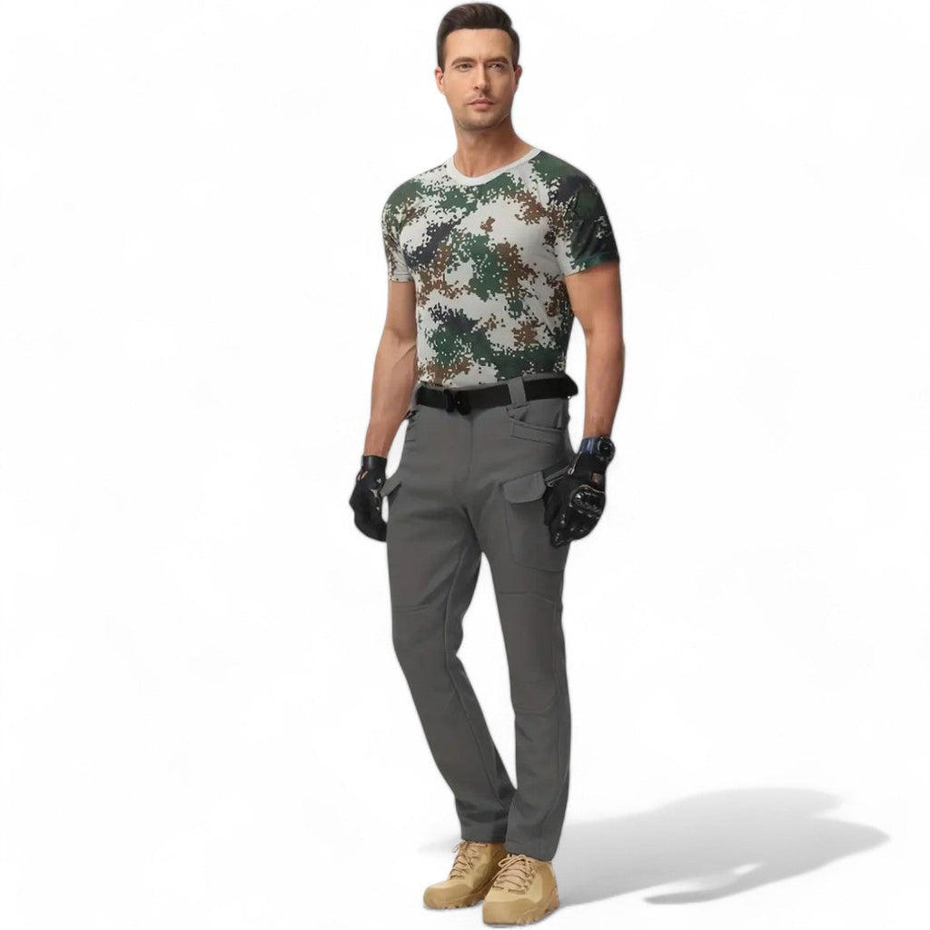 OUTDOORS NORDIC utility fleece pants in grey with multiple pockets, worn by a man in a camouflage t-shirt.