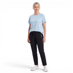A woman wearing an OUTDOORS NORDIC light blue quick-dry stretch t-shirt with black joggers and white sneakers.