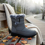 OUTDOORS NORDIC waterproof grey winter boots with faux fur lining and velcro strap on a wooden bench in a forest.