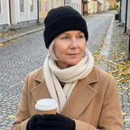 Woman in the black Cozy Waffle Beanie and a camel coat holding coffee on an autumn street