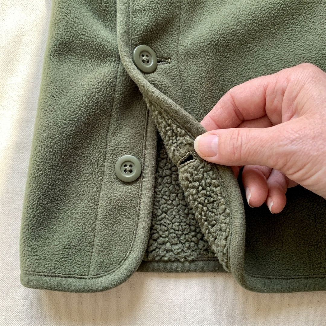 Närbild på sidslitsen med knappar på grön Sherpa Hoodie Vest