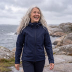 Kvinna i marinblå Utility Softshell Jacket på blåsig kustpromenad