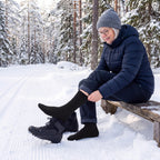 Kvinna i svarta Waterproof Hiking Socks tar på sig pjäxorna vid skidspåret